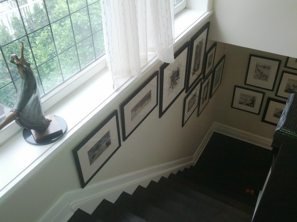 Un escalier avec beaucoup de tableaux encadrés au mur