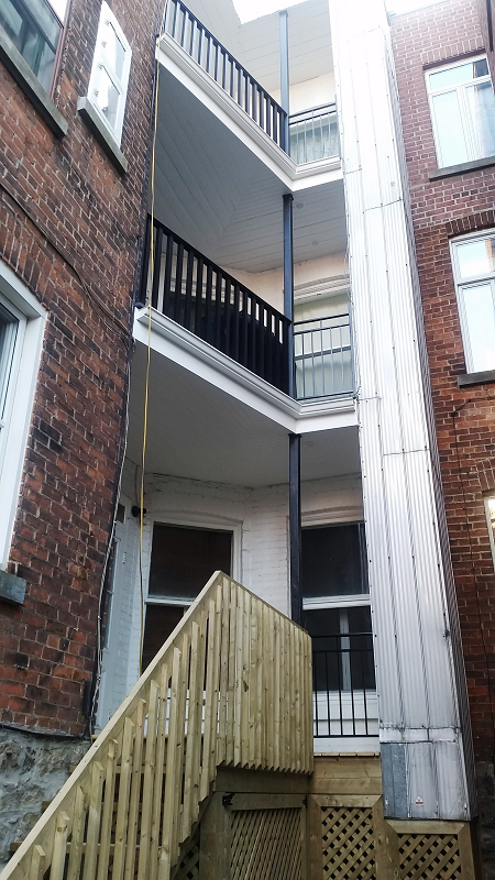 Un bâtiment avec une terrasse en bois et des escaliers qui y mènent.