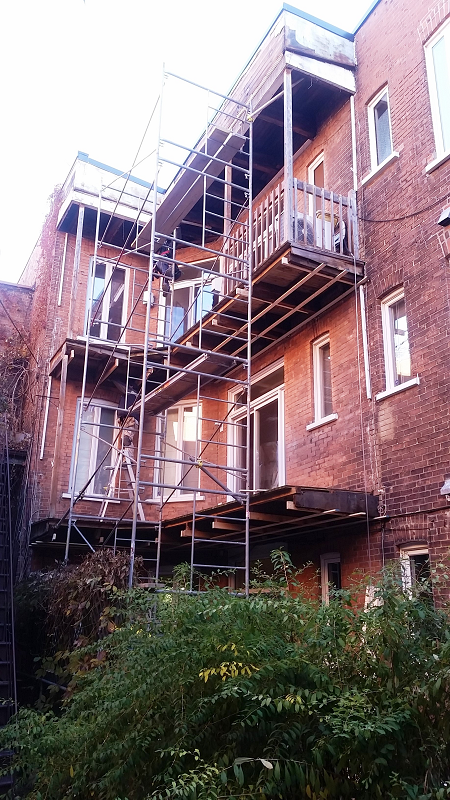 Un grand bâtiment en brique avec des échafaudages sur le côté.