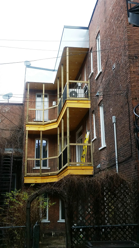 Un bâtiment en brique avec un balcon jaune sur le côté