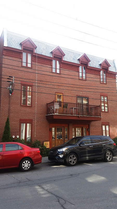 Deux voitures sont garées devant un grand bâtiment en brique