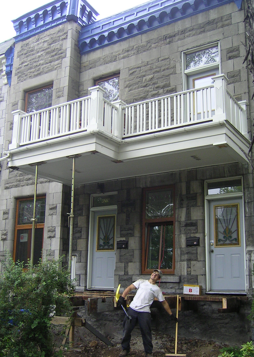 Un homme creuse devant un immeuble avec un balcon