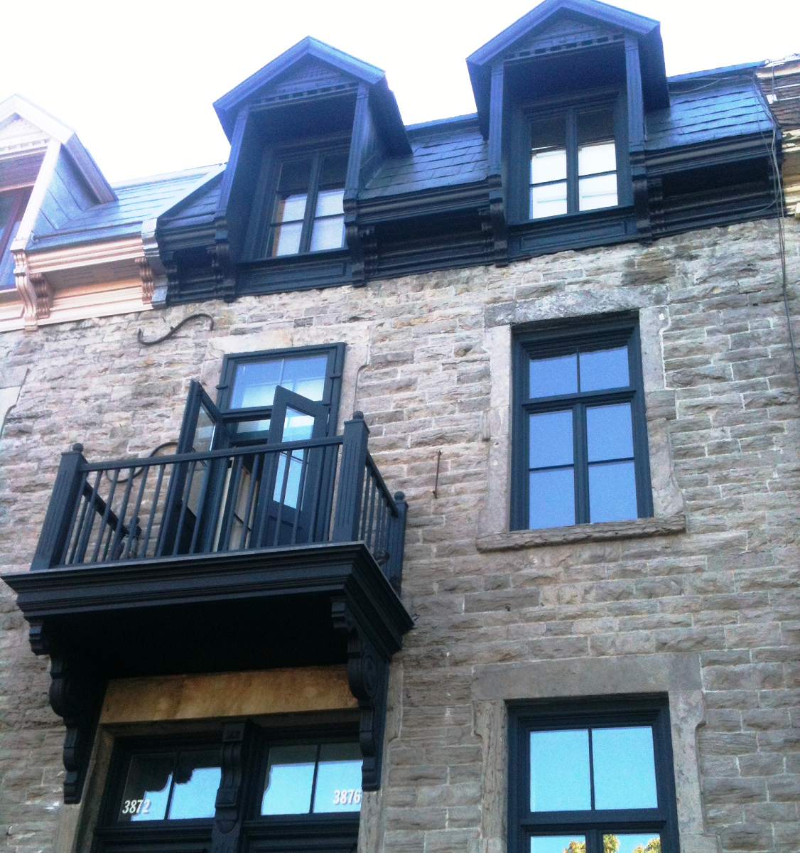 Un bâtiment en brique avec des fenêtres noires et un balcon