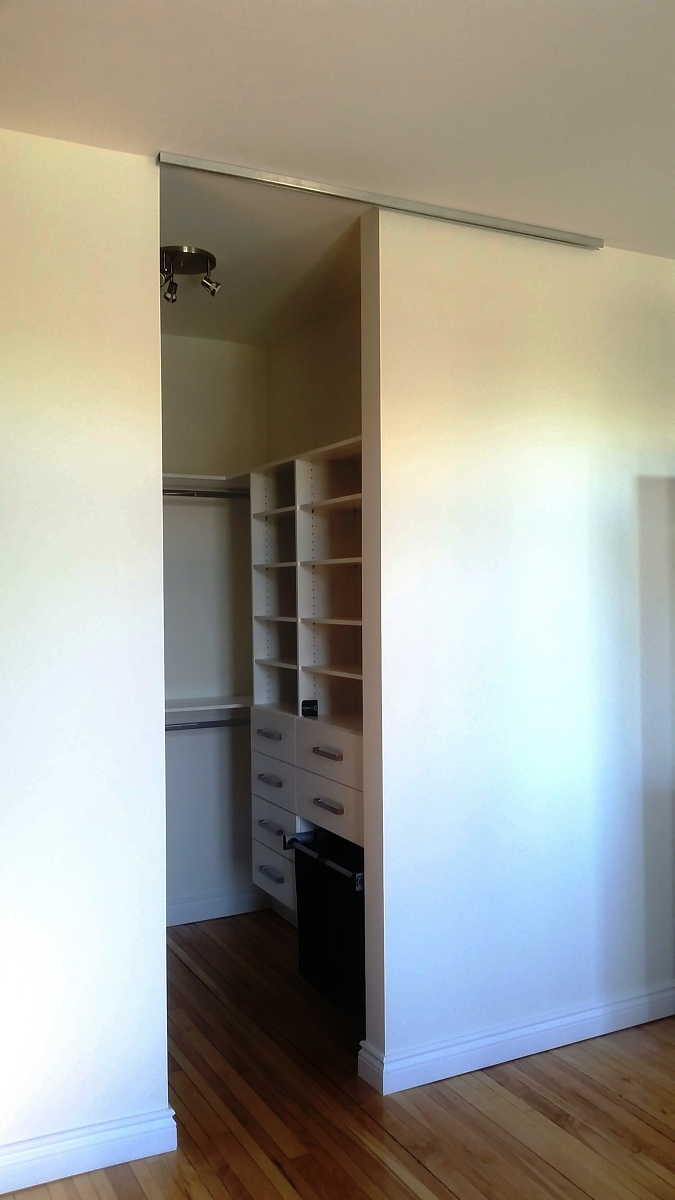Un dressing avec portes coulissantes et étagères