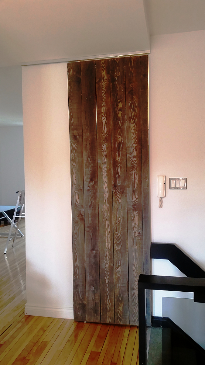 Une porte coulissante en bois se trouve dans une pièce à côté d'un escalier.