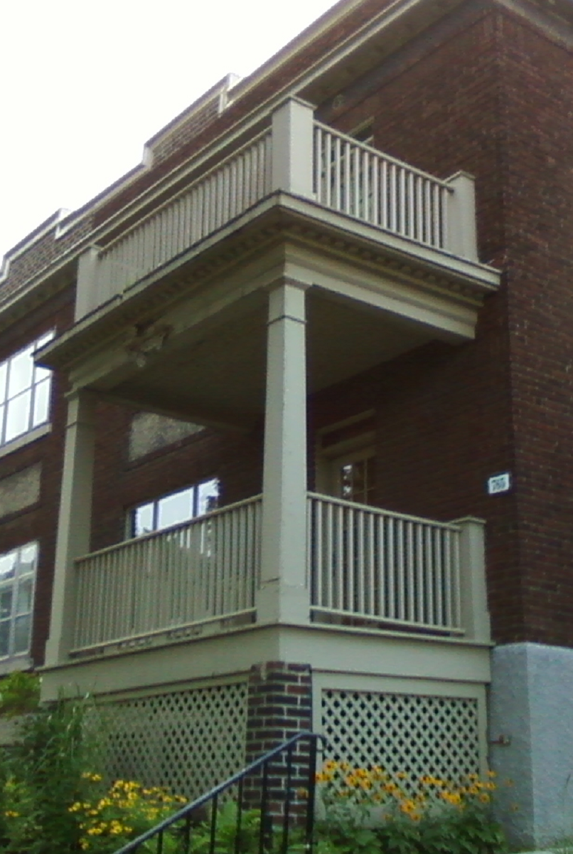 Un bâtiment en brique avec un porche et une balustrade blanche