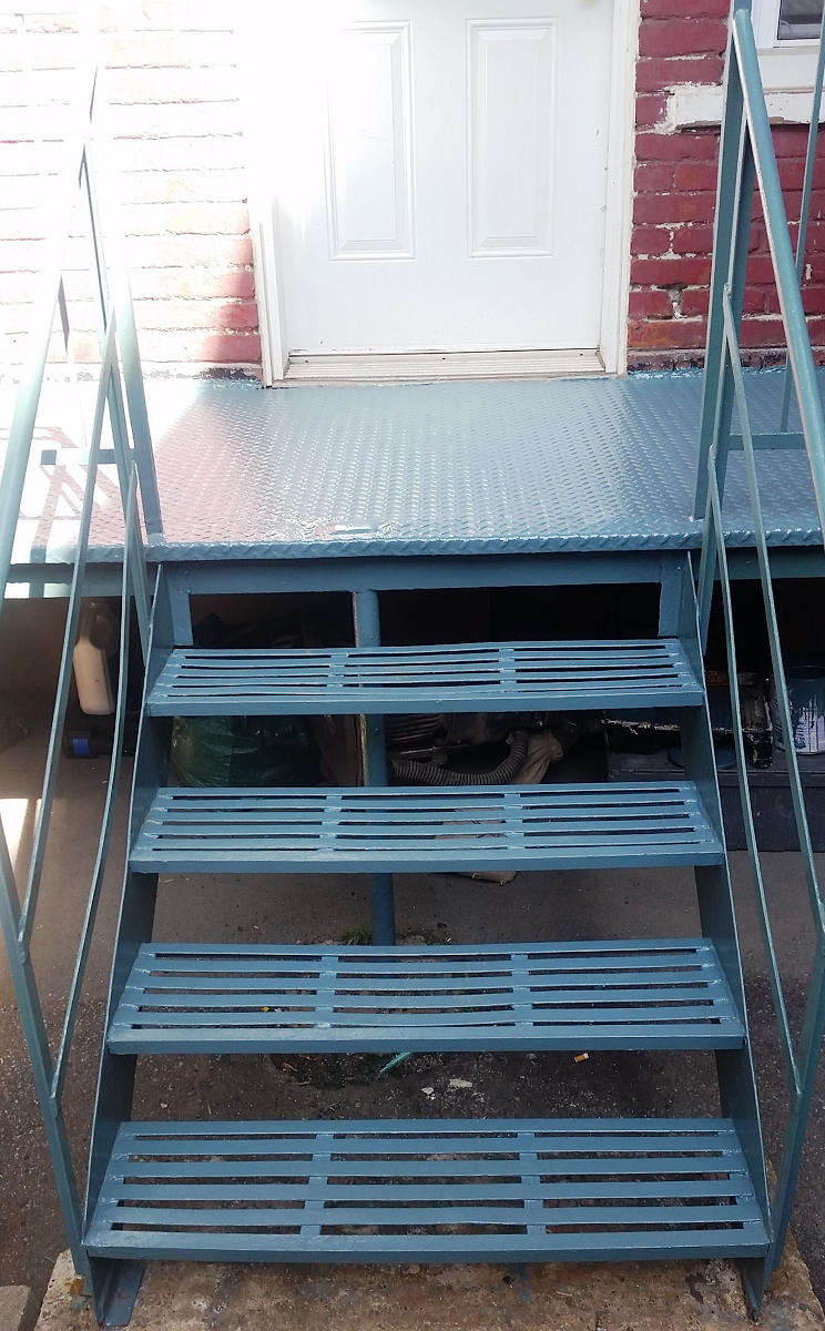 Un ensemble d'escaliers en métal bleu menant à un bâtiment en briques rouges.