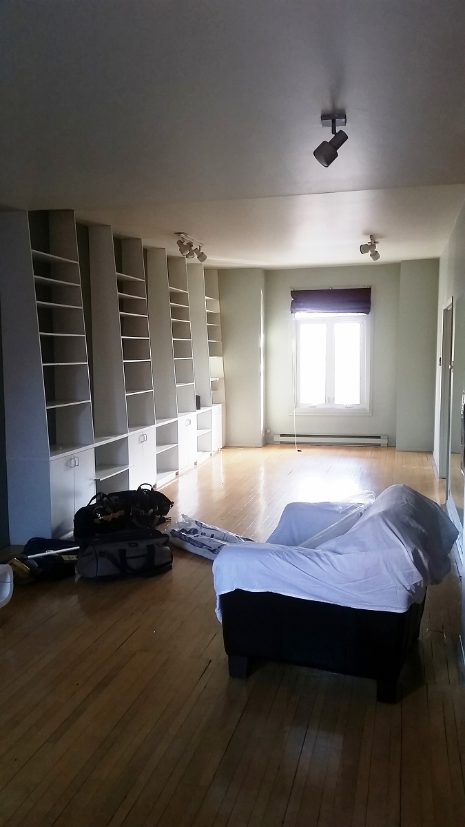 Un salon vide avec un canapé et une fenêtre.