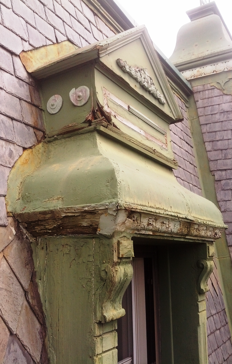 Un bâtiment en brique avec un toit vert et une fenêtre.