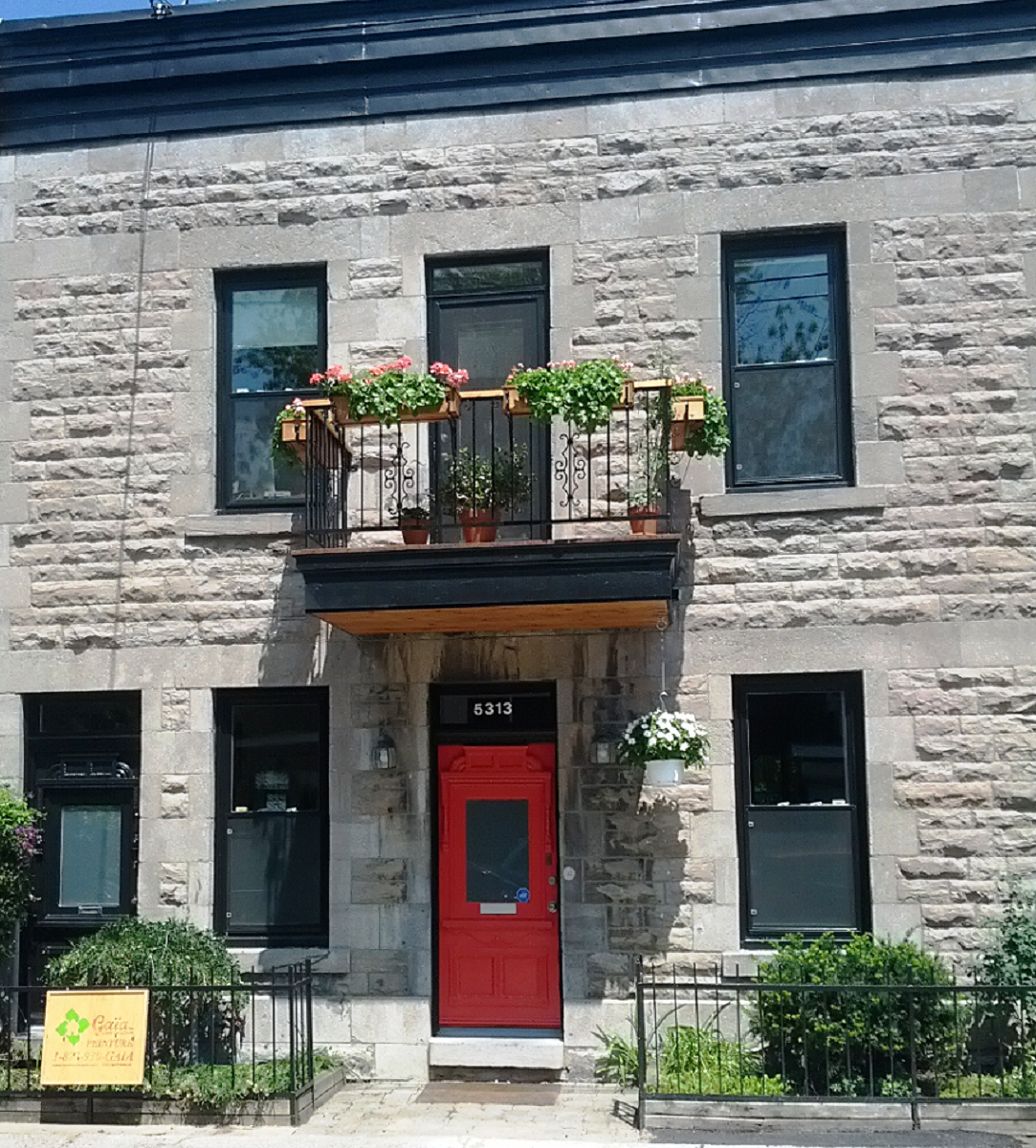 Un bâtiment en brique avec une porte rouge et un balcon
