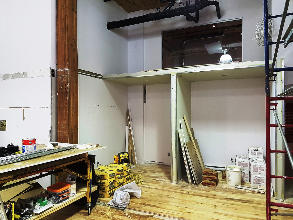 Une pièce en cours de rénovation avec du parquet et une échelle.