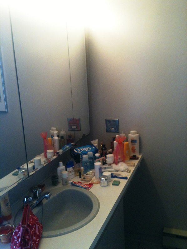 Une salle de bain avec un lavabo, un miroir et une boîte qui dit des cotons-tiges