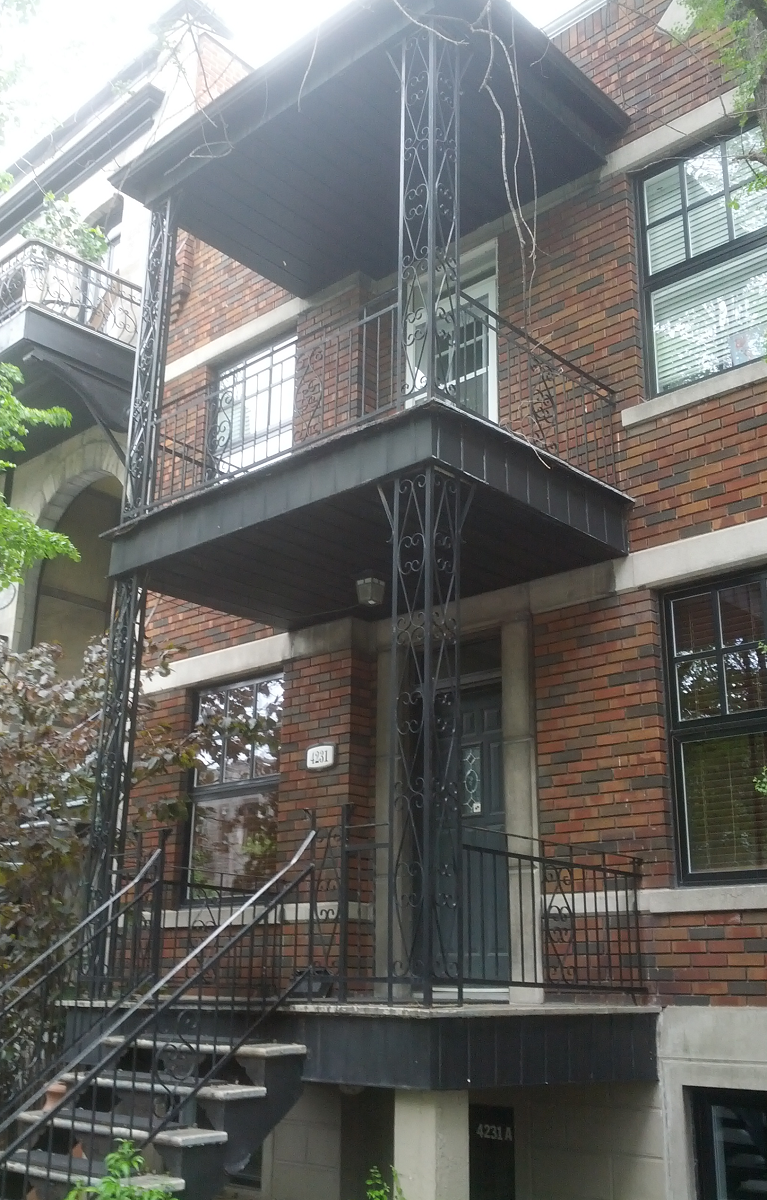 Un bâtiment en brique avec un balcon et des escaliers qui y mènent