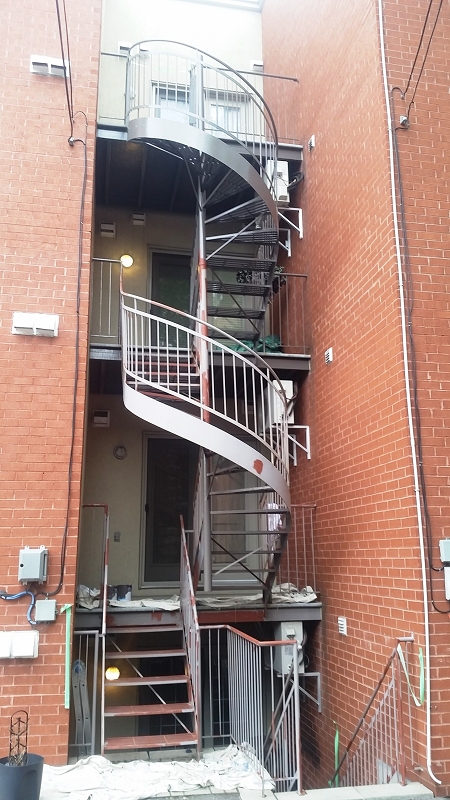 Un escalier en colimaçon monte sur le côté d'un immeuble en brique.