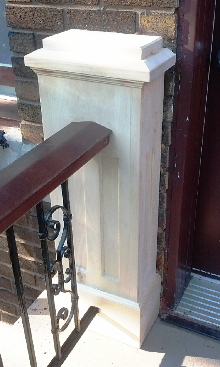 Un pilier blanc se trouve à côté d'une balustrade en fer forgé sur un balcon.