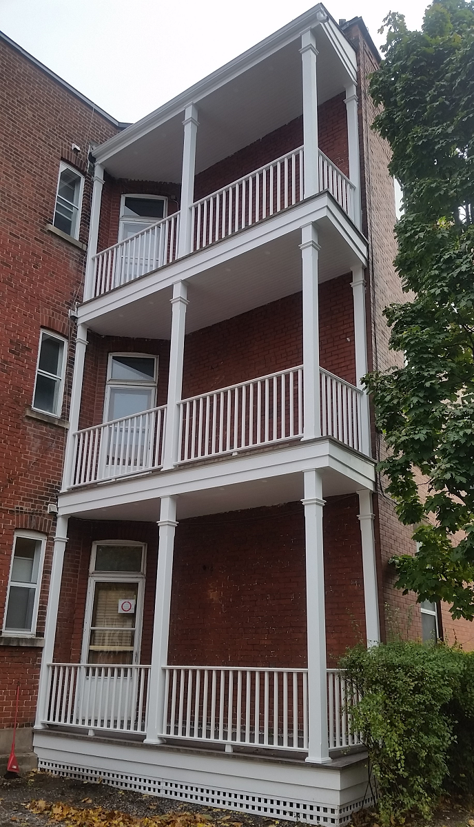 Un bâtiment en brique avec trois balcons et une balustrade blanche.
