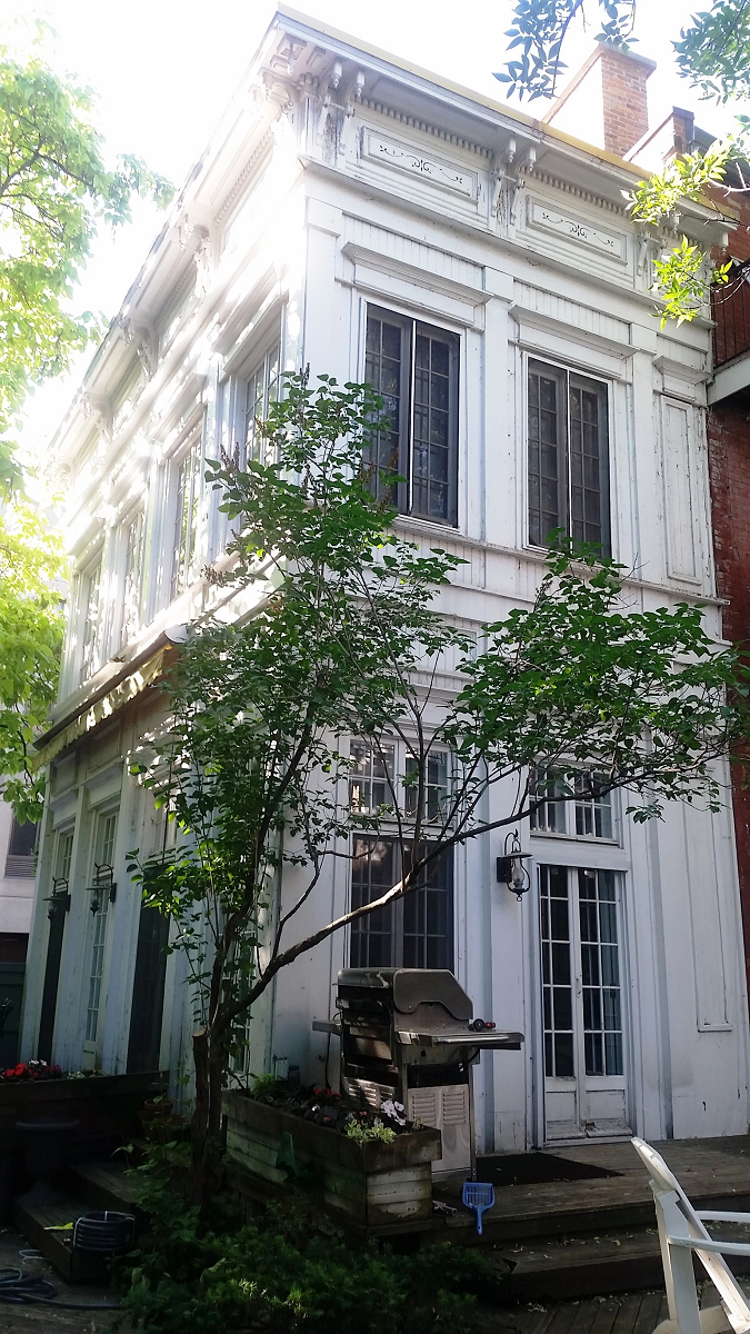 Un grand bâtiment blanc avec un grill devant lui entouré d'arbres.