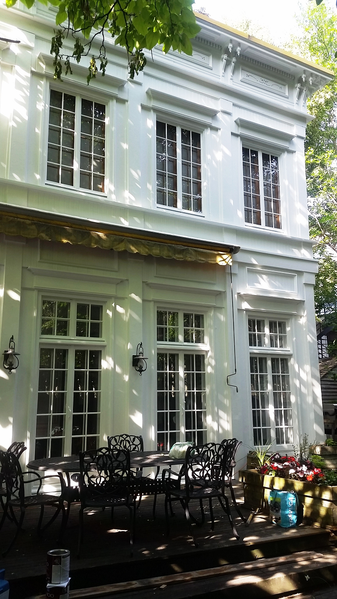 Un grand bâtiment blanc avec un patio et des chaises devant.
