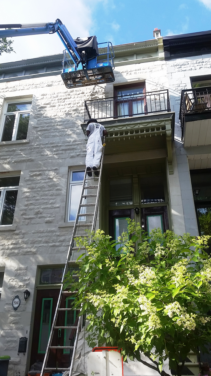 Un homme se tient debout sur une échelle sur le côté d'un immeuble.