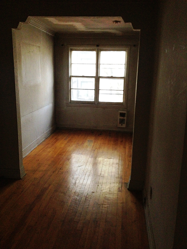 Une pièce vide avec du parquet et une fenêtre.