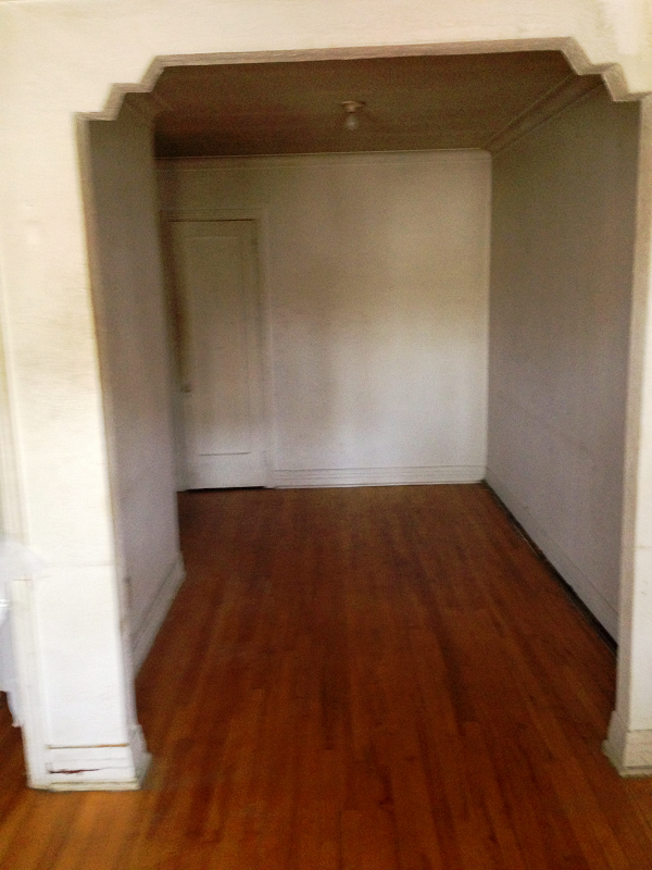 Une pièce vide avec du parquet et des murs blancs.