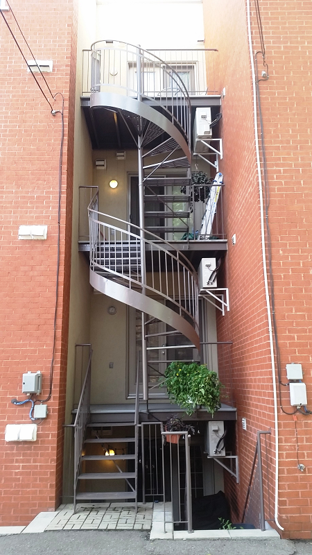 Un escalier en colimaçon se trouve entre deux bâtiments en brique.