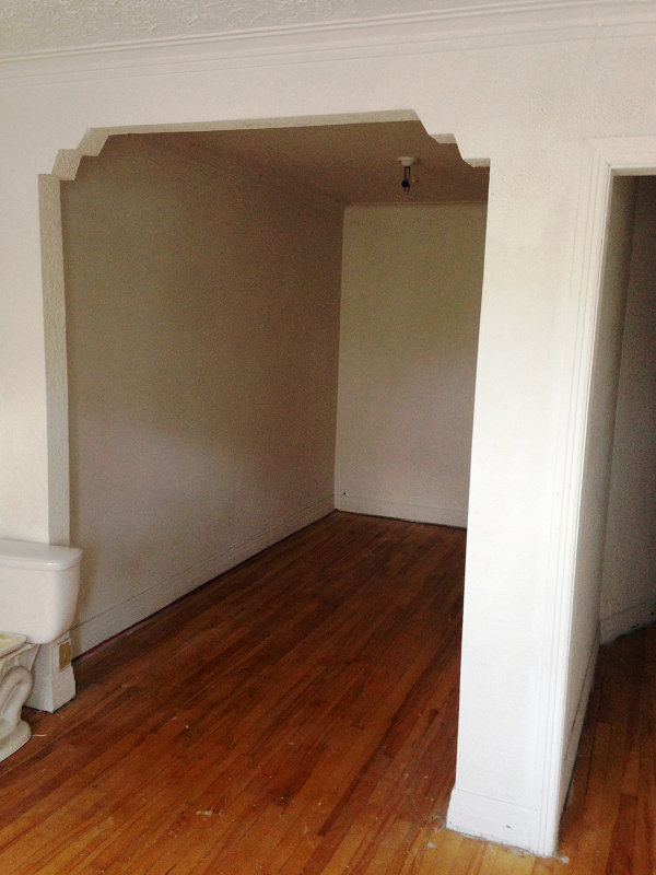 Une pièce vide avec du parquet et des murs blancs.