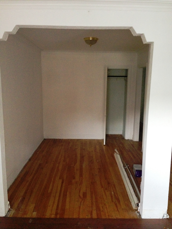 Une pièce vide avec du parquet et des murs blancs.