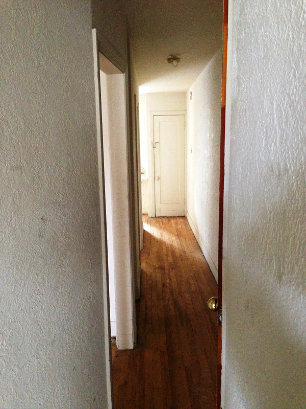 Un couloir avec parquet et murs blancs
