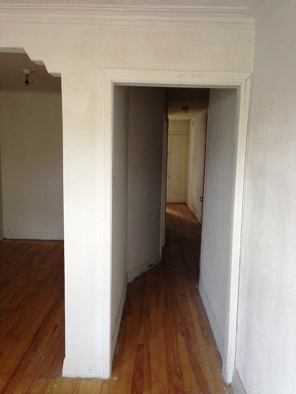 Un couloir vide avec parquet et murs blancs