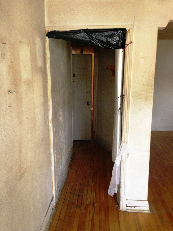 Un couloir avec du parquet et une porte blanche
