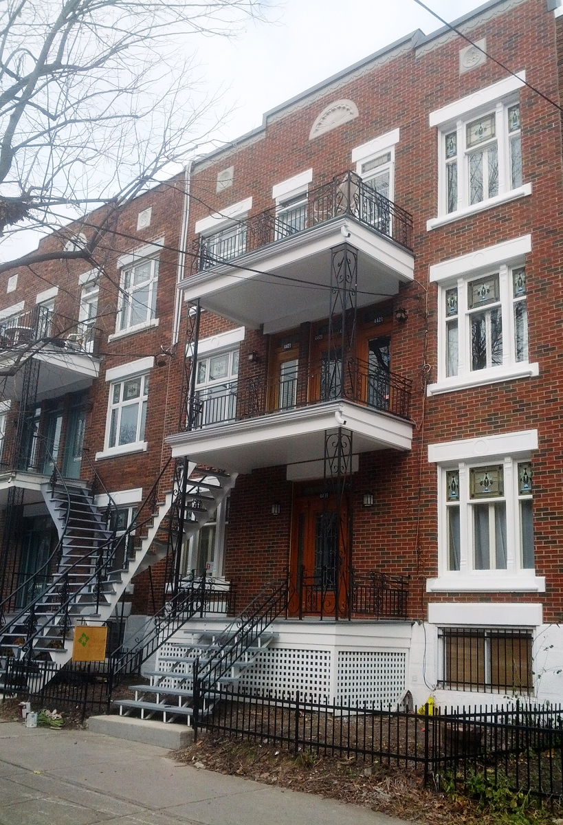 Un grand immeuble d'appartements en brique avec balcons et escaliers.