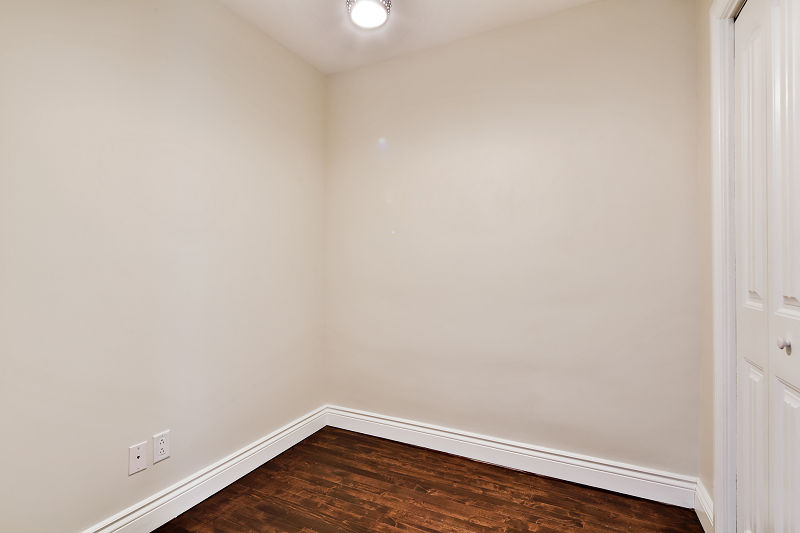 Une pièce vide avec du parquet et des murs blancs.
