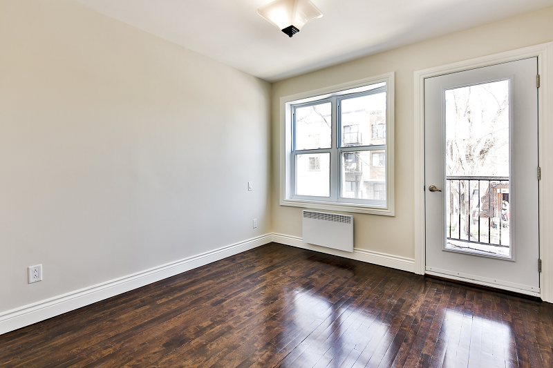 Une pièce vide avec du parquet et une fenêtre