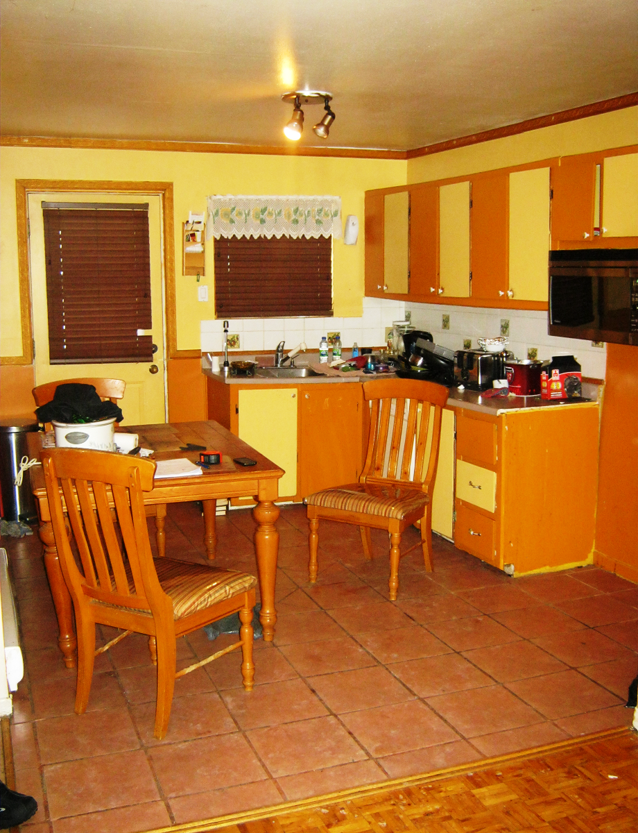 Une cuisine avec armoires orange et une table et des chaises