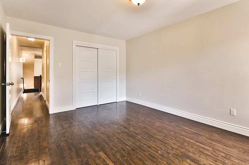 Une chambre vide avec du parquet et des murs blancs.