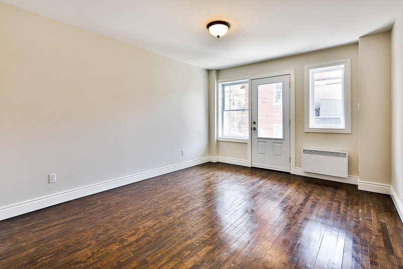 Un salon vide avec parquet et porte.