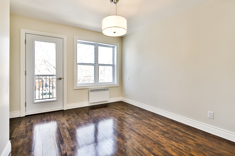 Une pièce vide avec parquet et balcon.