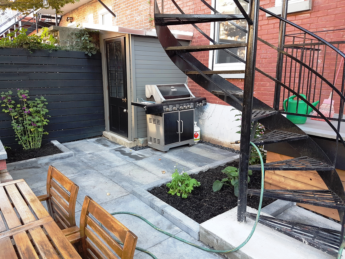 Une cour avec un grill et des escaliers ainsi qu'une table et des chaises.