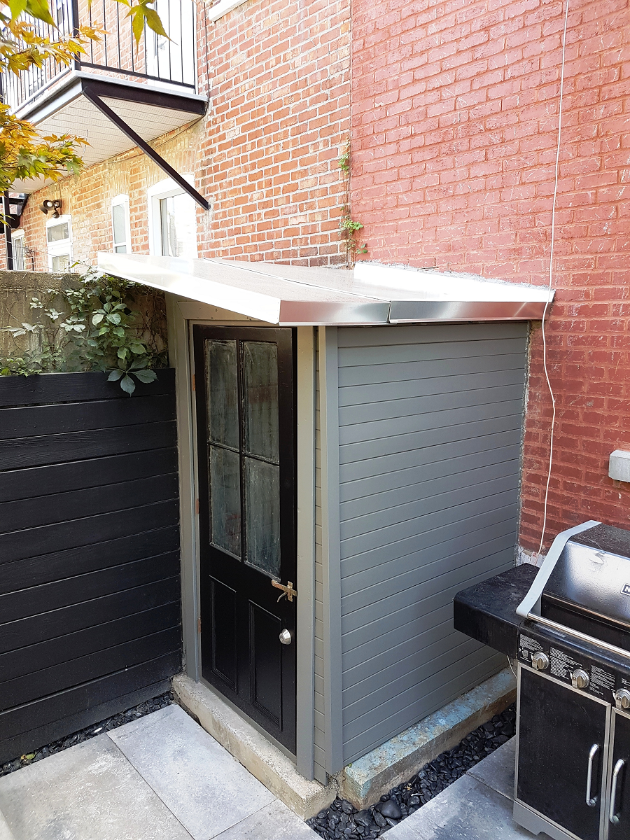 Un bâtiment en brique avec un hangar et un grill devant.