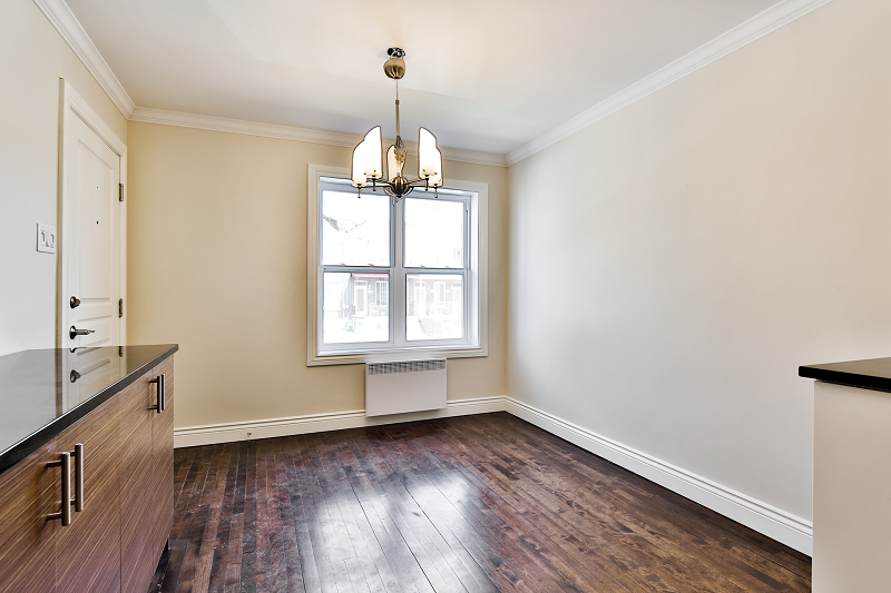 Une pièce vide avec du parquet et un lustre