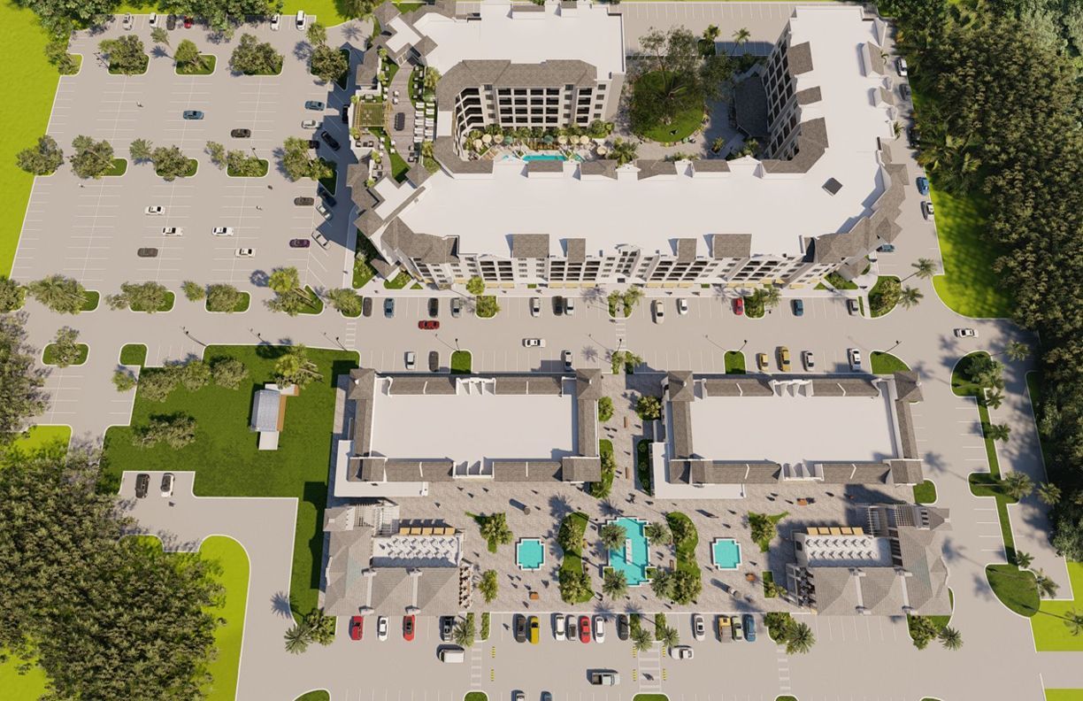Aerial view of a large, white commercial building with parking, trees, and landscaping.