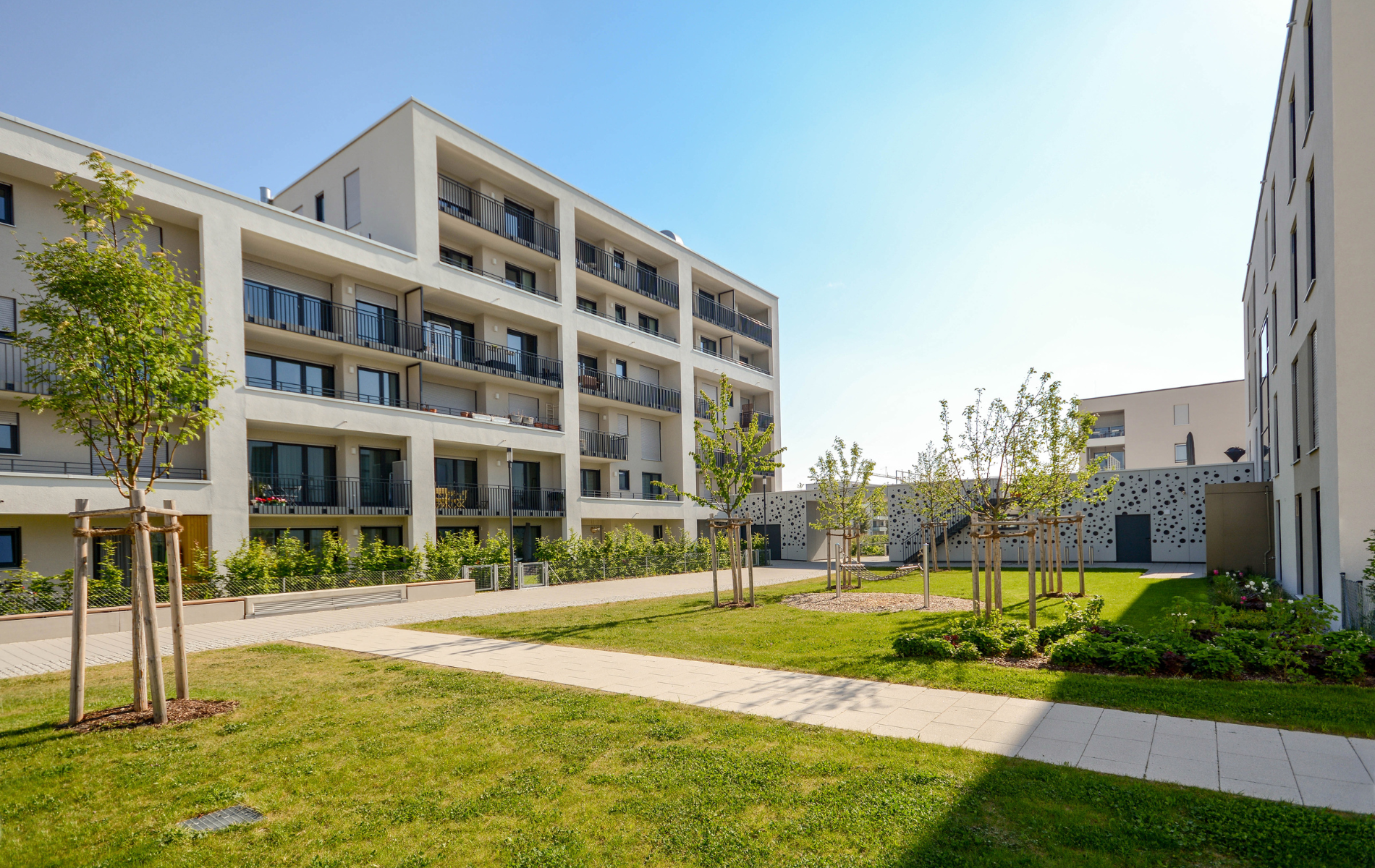 A row of apartment buildings with a lush green lawn in front of them.