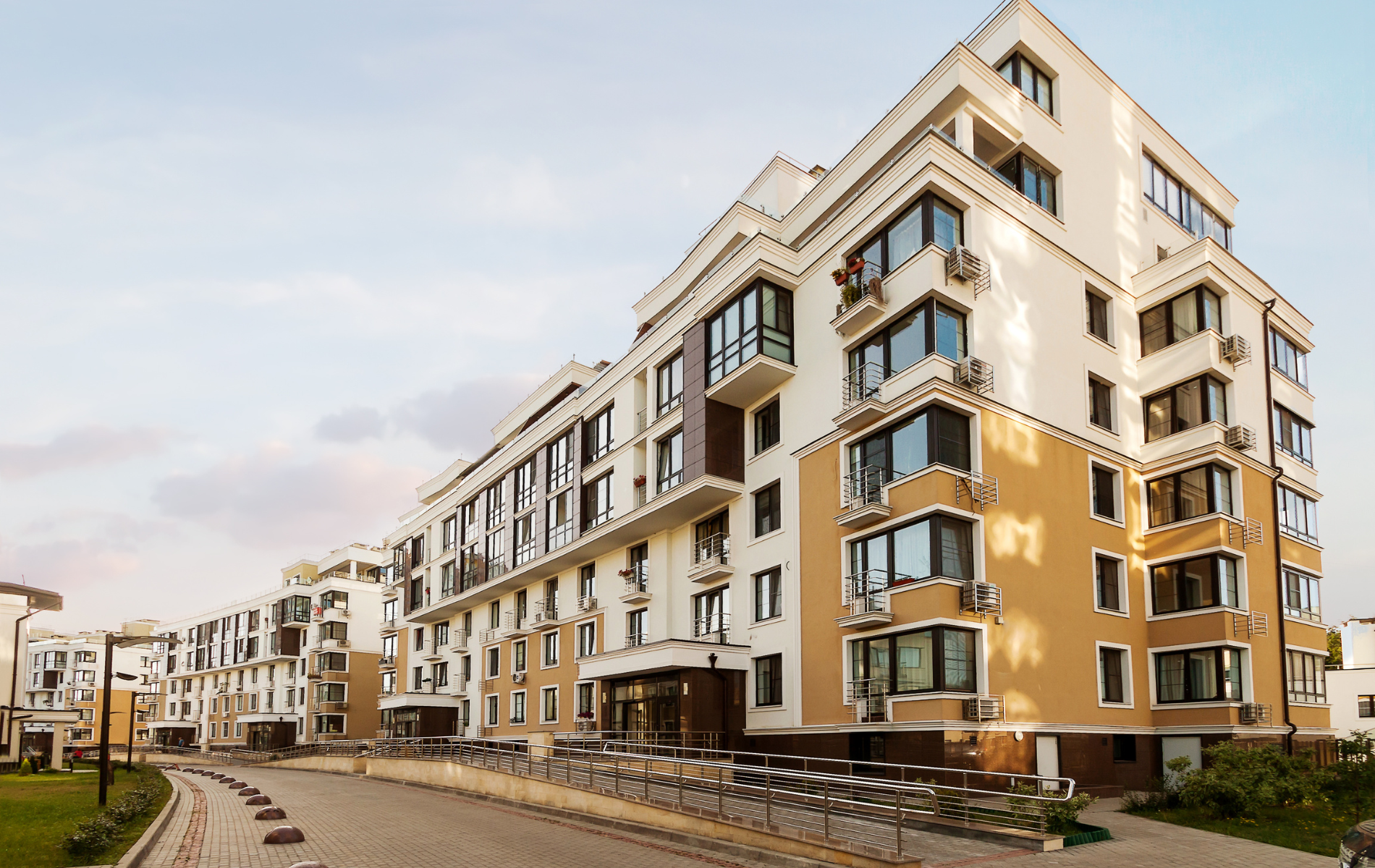 A large apartment building with a lot of windows and bicycles parked in front of it.