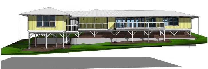 Yellow house on stilts with a white roof and a deck with railings. It sits on a grassy hill, with a gray shadow below.