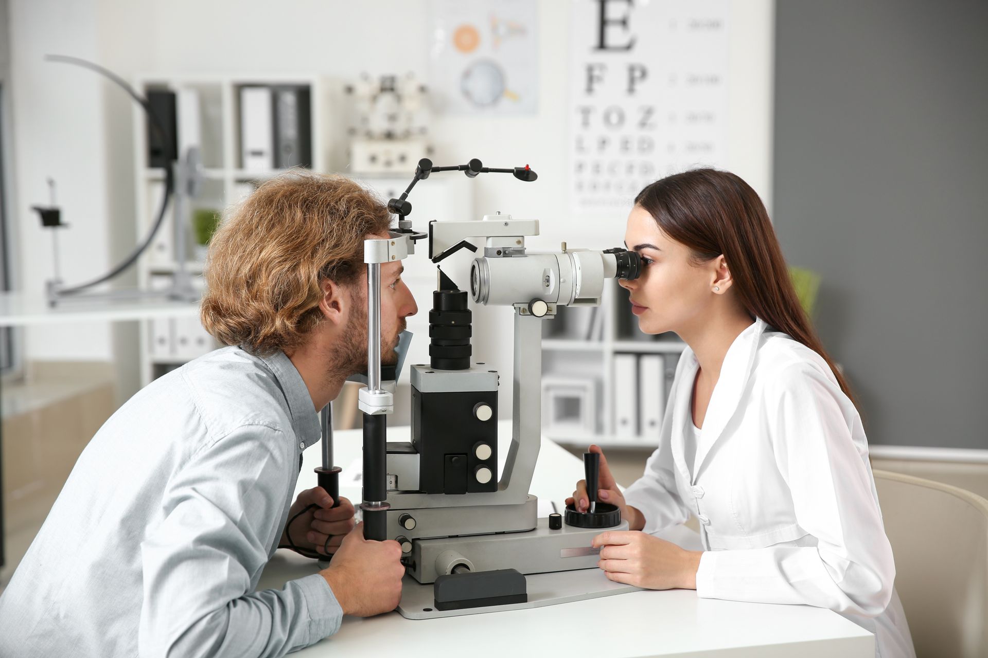 An eye doctor examining a young man in a clinic for routine eye care and a vision check-up.