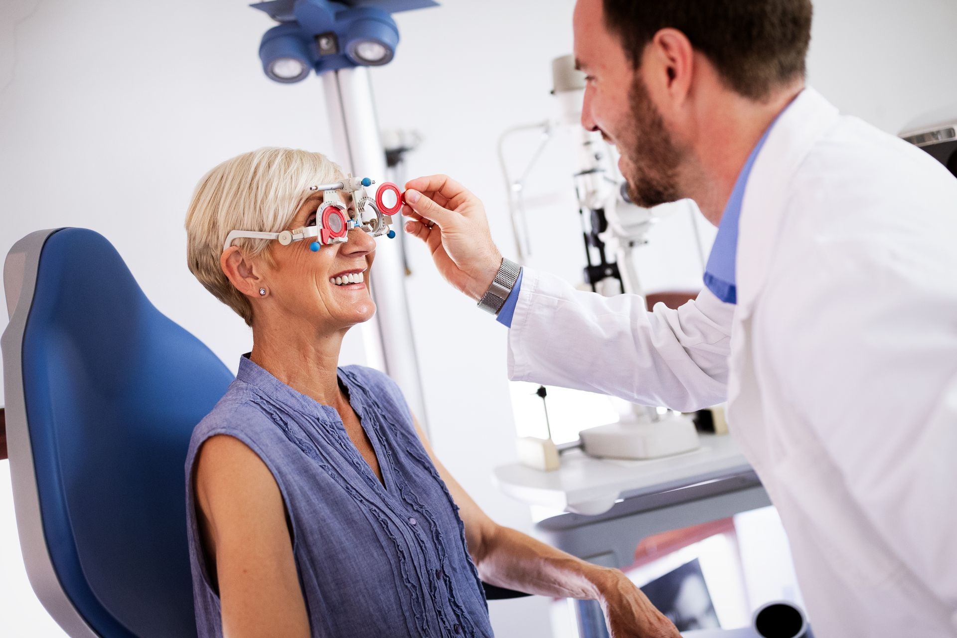 An eye doctor adjusting a phoropter during a patient's vision exam in a clinic.