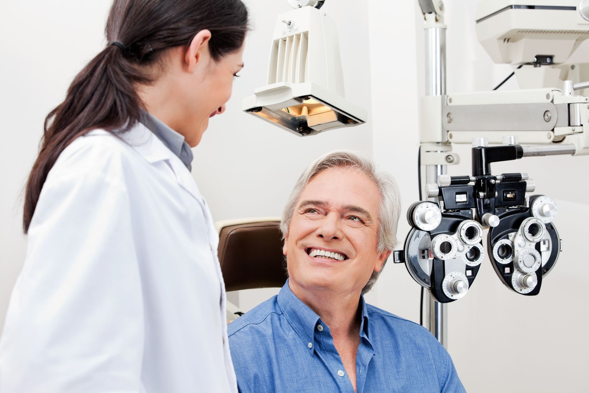 An eye doctor smiling with a patient during a routine vision exam.