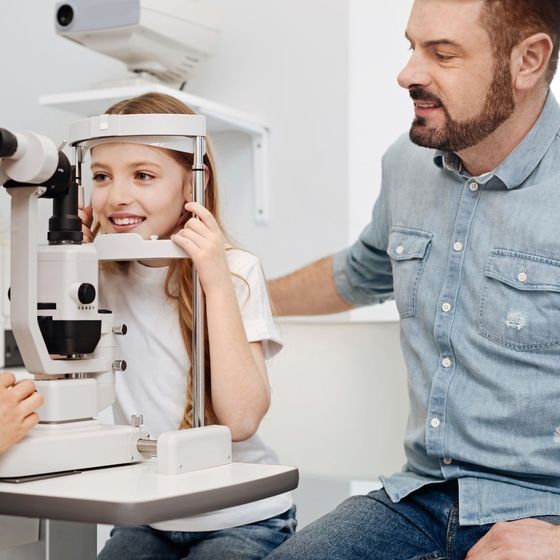 A little girl is getting her eyes examined by an ophthalmologist.