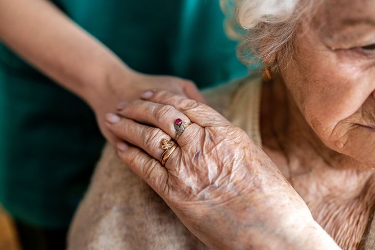 Old lady touching the hand of the nurse